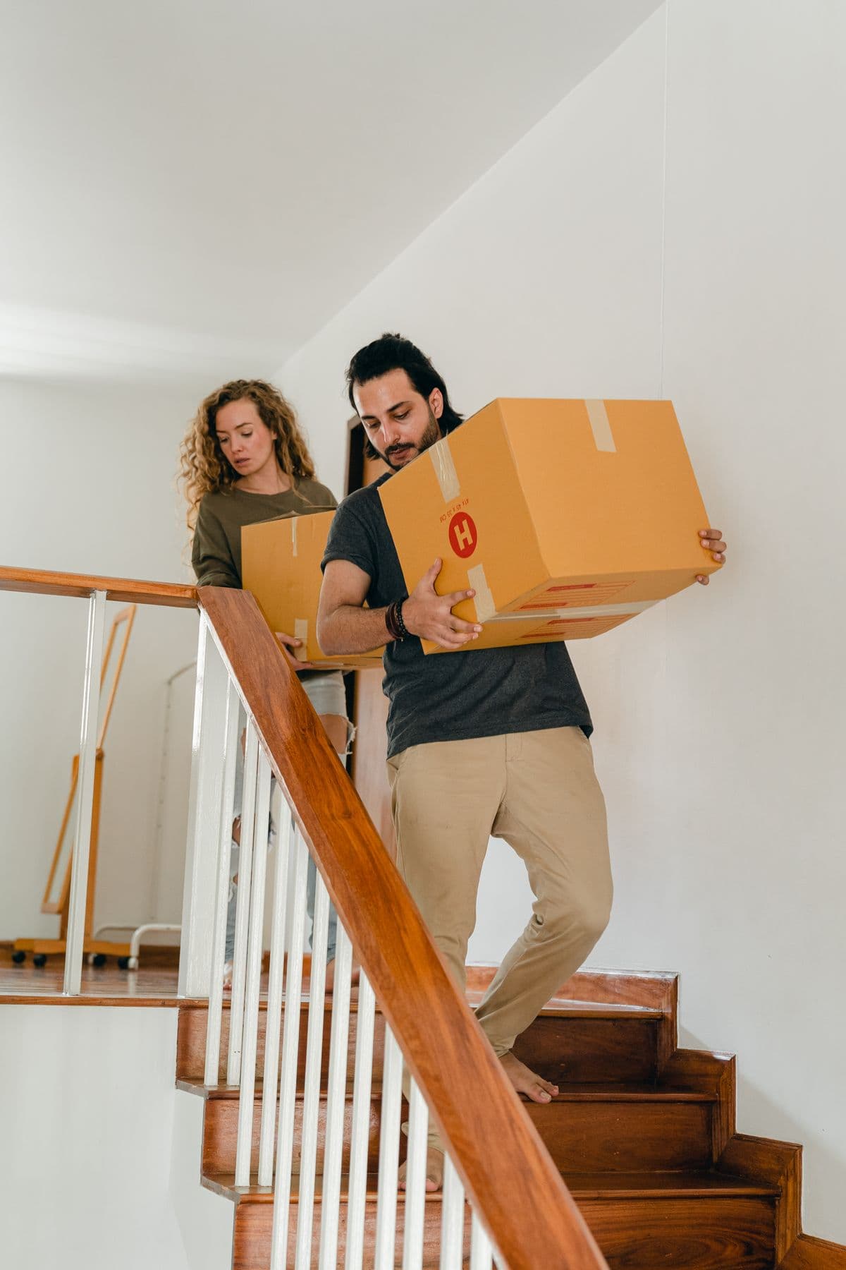 A couple carrying cardboard moving boxes into their new home