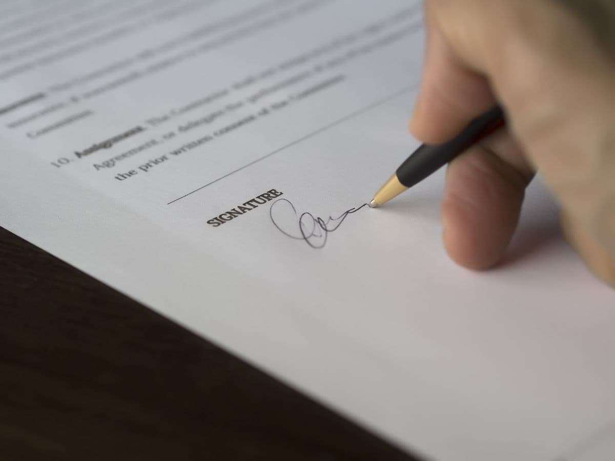 A hand signing a tenancy agreement with a pen at the signature line