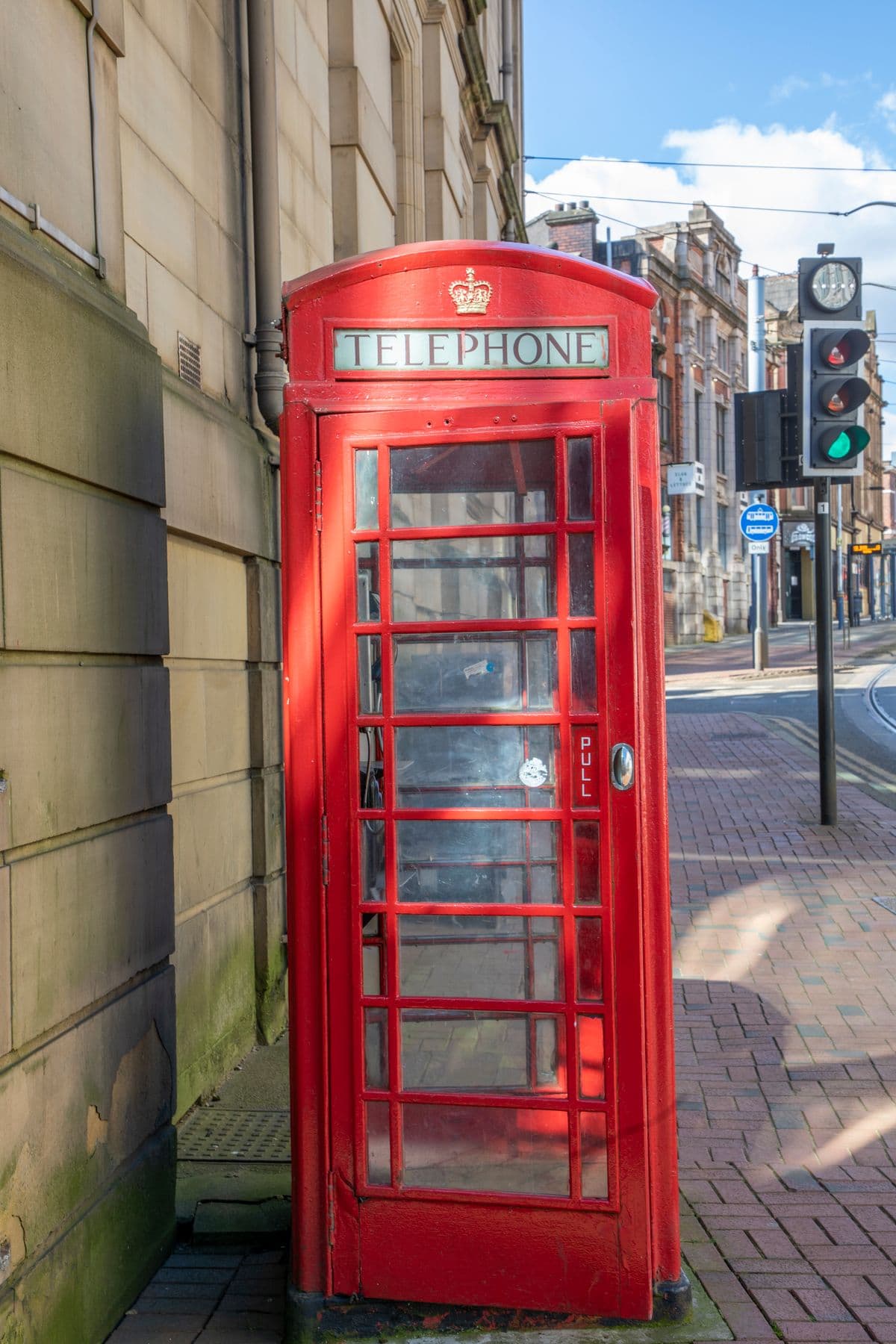 A red telephone box on a Sheffield street beside the tram tracks