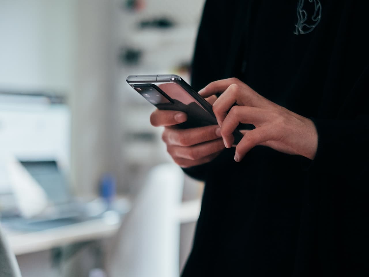 Person tapping on a smartphone, checking a verified listing
